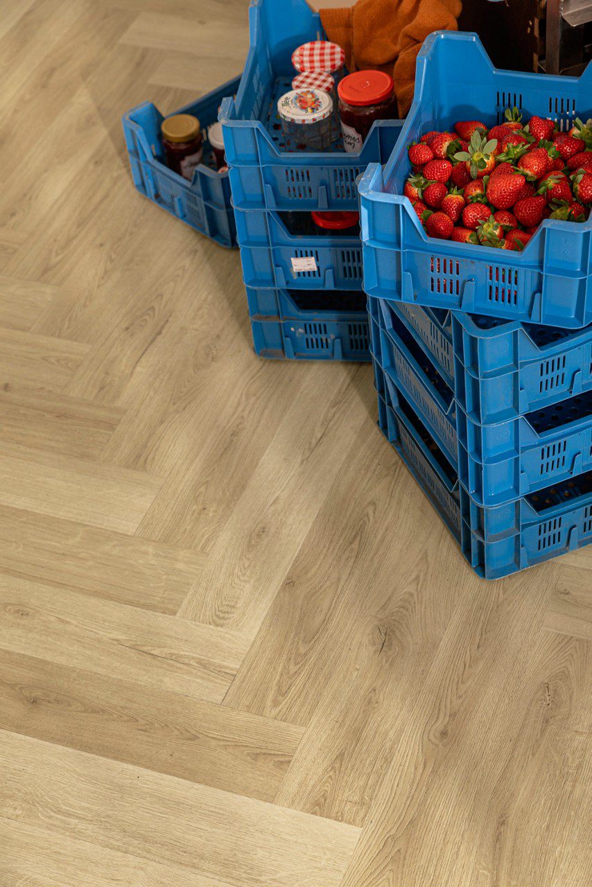 SPC herringbone flooring Quick-Step Ciro Botanic Beige installed on floor and strawberry's and jam in the boxes