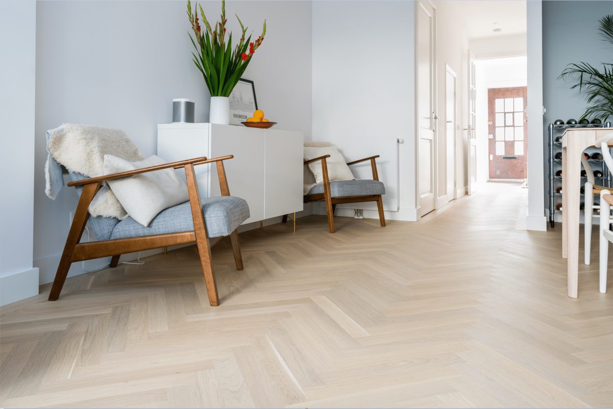 Kalanruotoparketti Bauwerk Monopark tammi 45 Crema B-Protect asennettu keittiön ja eteisen lattialle. Nojatuolit, kaappi, kukat, appelsiinit, viiniteline, ruokapöytä.