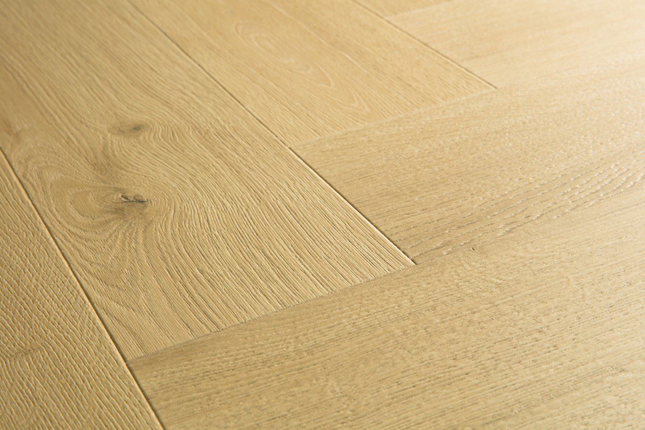 Kalanruoto laminaatti Quick Step Pergo Impressive Design Ginger Oak, lämmin keskiruskea tammen sävy ja tasainen lajitelma, vesilätäkkö osoittamassa vedenkestävyyttä