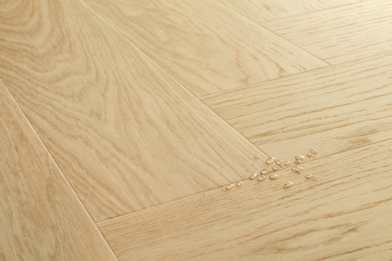 Vinüülparkett kalasaba Quick-Step Ciro Pure Oak Blush tooni ja disaini kirjeldus veepiiskadega põrandal viitamaks veekindlusele
