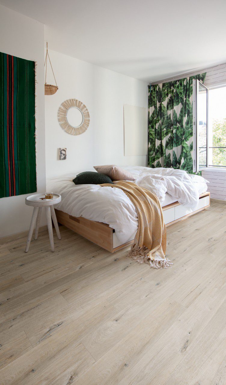 LVT floor Quick-Step Bloom Cotton Oak White Blush installed on a children's room floor. Bed, curtains with green leaf design.