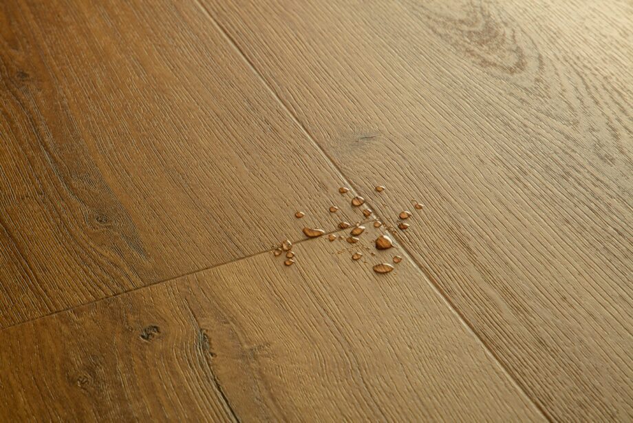 LVT parkett Quick-Step Bloom Botanic caramel oak tooni ja disaini kirjeldus. Veepiisad parketil viitamaks veekindlusele.