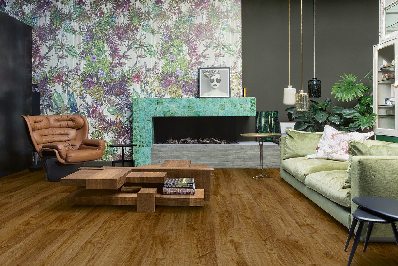 Vinyylilattia Quick Step Bloom Autumn Oak Brown asennettuna olohuoneen lattialle, takka, sohva, sohvapöytä, nojatuoli ja vitriinikaappi.