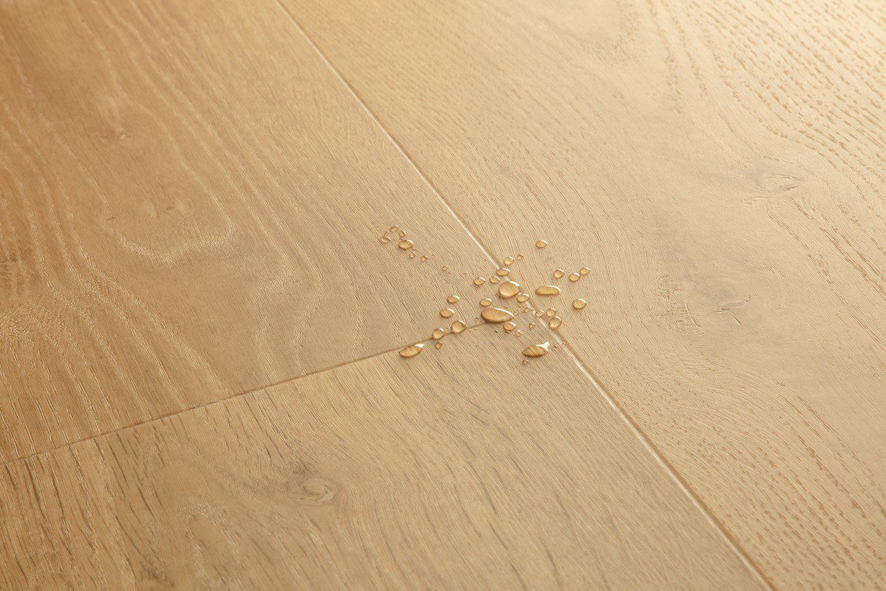 Vinyylilattia Quick Step Bloom Elegant Oak Natural, luonnollinen tammen sävy ja lankkudesign, pinnalla vesipisaroita korostamassa lattian vedenkestävyyttä.