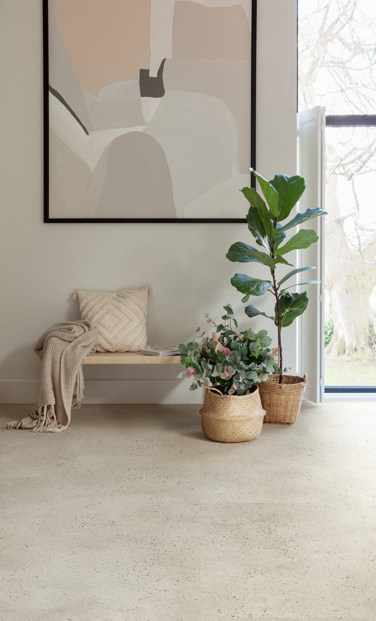 Vinyl floor tiles Quick-Step Illume Oyster concrete installed on hallway floor. Bench, painting on a wall, plants.