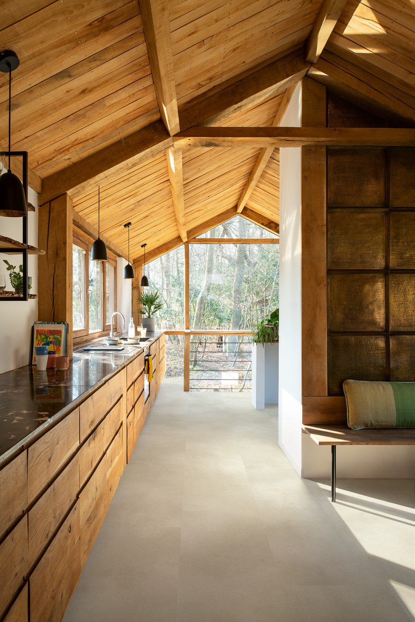 Vinyl flooring tiles installed on a 1-st floor kitchen. Rustical stile with wooden beams and boards ceiling. Rustical wooden kitchen furniture facade with dark marble top. Rustical golden wall tiles.