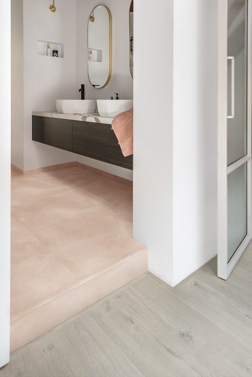 Vinyl tile flooring Quick-Step Illume Soft blush installed on a bathroom floor. Bathroom furniture.