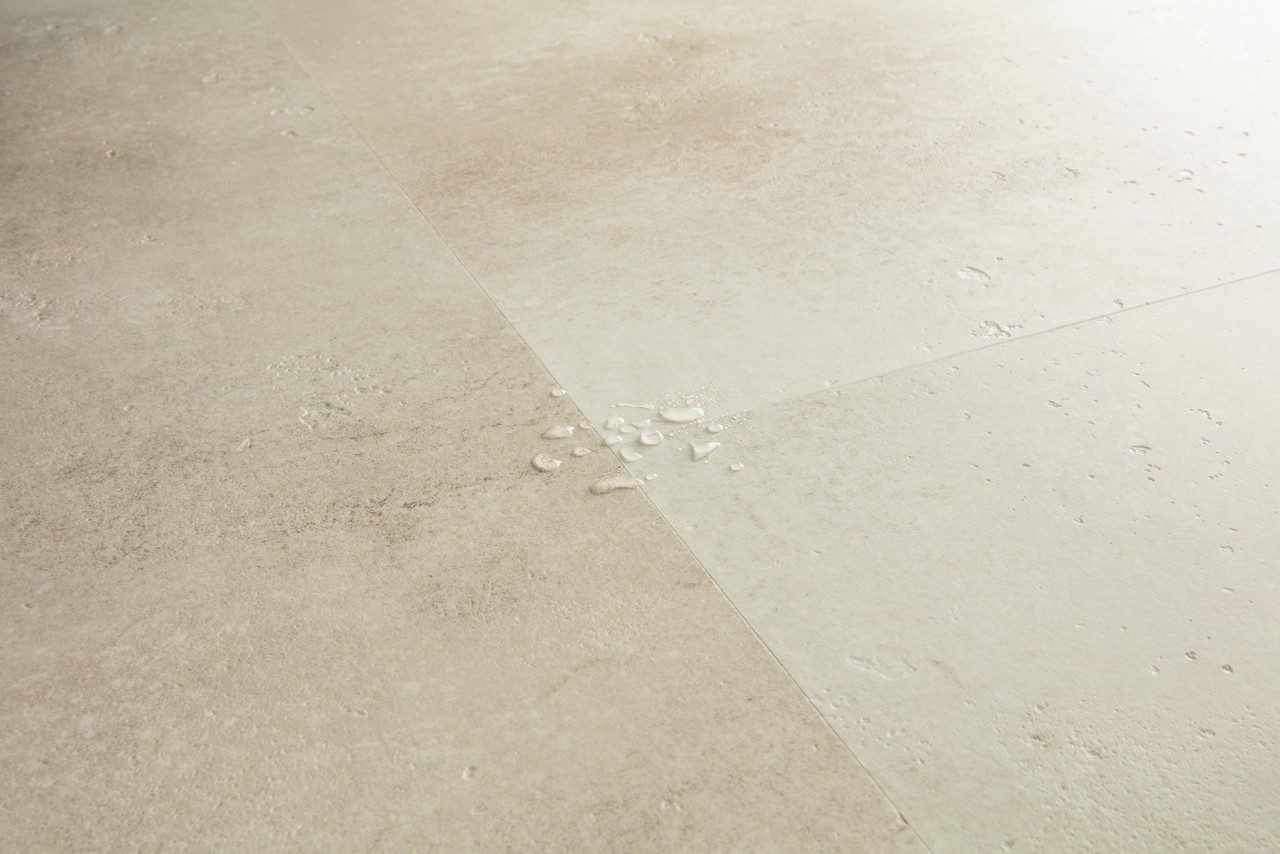 Vinyylilaatta Quick-Step Illume Sandstone Concrete asennettuna modernin kodin lattialle – lämmin hiekkabeige/greige sävy ja luonnollisen pehmeä betonidesign, jossa on hienovarainen kivimäinen tekstuuri.