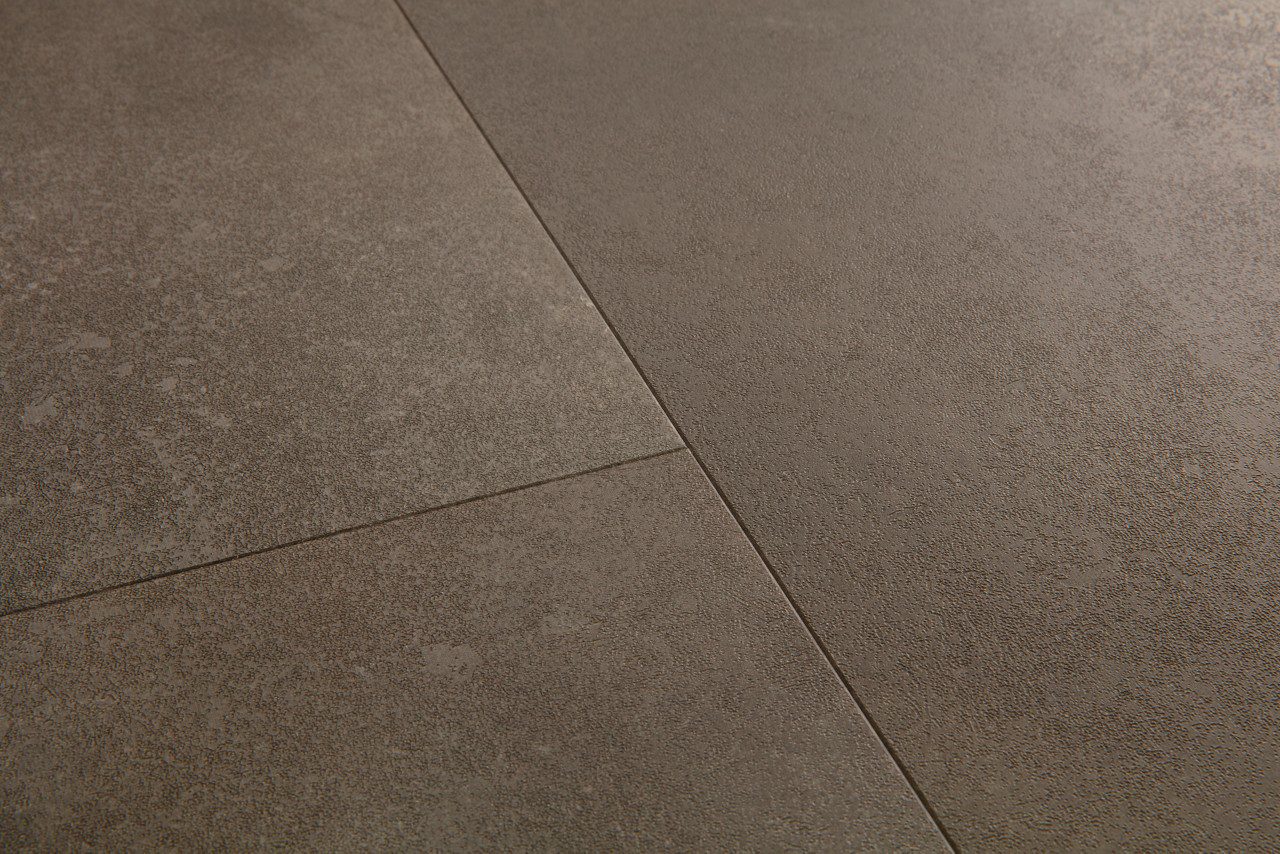 Vinyylilaatta Quick Step Oro Oxidized Rock asennettu lattialle ruosteisen kuparin ja lämpimän ruskean sävyinen kivikuosi teollishenkinen ja elävä pinta hienovarainen struktuuri ja luonnollinen sävyvaihtelu kestävä ja helppohoitoinen vinyylilattia sisustuksessa