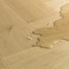 Kalanruotolaminaatti Quick Step Pergo Impressive Design Gardamom Oak, vaaleanruskea tammen sävy ja tasainen lajitelma, vesilätäkkö osoittamassa vedenkestävyyttä