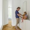 laminat-fischgrat-quick-step-impressive-design-cinnamon-oak Vinylboden Fischgrät Quick Step Impressive Design Cinnamon Oak, verlegt im Badezimmerboden, Vater lässt Wasser aus dem Hahn laufen und das Kind sitzt auf der Badezimmermöbelplatte