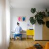 Klickvinyl Quick Step Bloom Botanic Smoked Oak im Wohnzimmer verlegt, orangefarbener Liegesessel, ein Mann sitzt auf einem Stuhl und spielt einen Synthesizer.