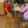 LVT floor Quick-Step Bloom Botanic caramel oak installed on dining room floor. Father, mother and daughter are having lunch.