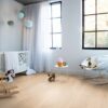 vinyylilankku-quick-step-bloom-pure-oak-blush Vinyylilankku Quick Step Bloom Pure Oak Blush asennettuna lastenh uoneen lattialle, vaalea tammen sävy kevyellä punertavalla vivahteella ja lankkudesign, kehto, keinul hevonen, tuoli ja leluja.