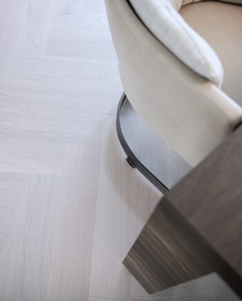 Fiskbensparkett Bauwerk Monopark ek Natur 15 Farina B-Protect® vit mattlack – närbild på det ljusa ekgolvet under stol och bord