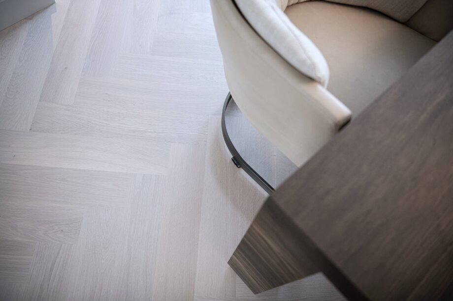 Bauwerk Monopark ek Natur 15 Farina i fiskbensmönster Fiskbensparkett Bauwerk Monopark ek Natur 15 Farina B-Protect® vit mattlack – närbild på det ljusa ekgolvet under stol och bord